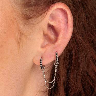 Woman Wearing Silver Black Stone Huggie Hoop Earrings with Double Chain Connector