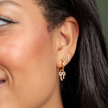 gold sparkling Bow charm hoop earrings perfect for lobe piercings shown on model
