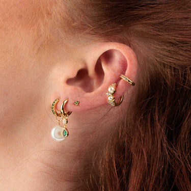 Close-up of green and pearl ear stack with emerald green trinity stud earrings