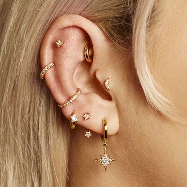 Large huggie earring worn in conch piercing as part of an ear stack on model