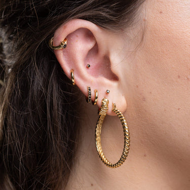 Huggie earrings with black stones worn in upper cartilage lobe piercing