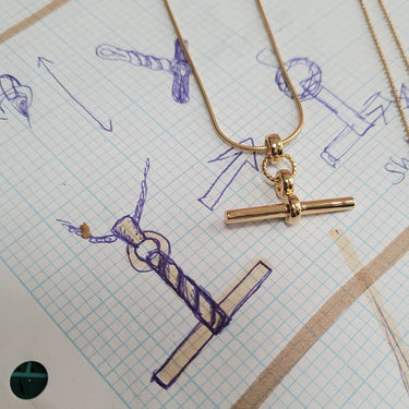 Gold T-Bar Necklace with Snake Chain Next to Design Drawing