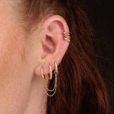 Woman Wearing Gold Clear Stone Huggie Hoop Earrings with Double Chain Connector with Huggie Earrings