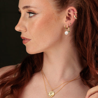 Woman Wearing an Emerald Green and Pearl Ear Stack with Charm Hoops, Studs and Huggie Earrings