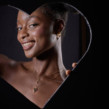 Woman Wearing Heart Charm Necklace, Cross Necklace and Heart Charm Hoop Earrings