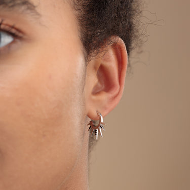 Woman Wearing Silver Sun Spike Hoop Earrings with Black Stones