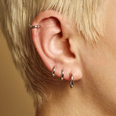 Mini huggie earring worn in helix piercing on model