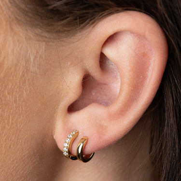 Mismatched Double Gold Huggie Earrings with Clear Stones on ear