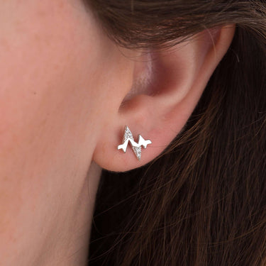Woman Wearing Silver Heartbeat Stud Earrings with Clear Stones
